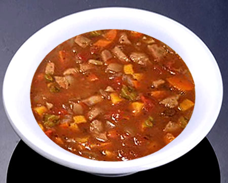 Овощной суп с томатом и колбасой в тарелке