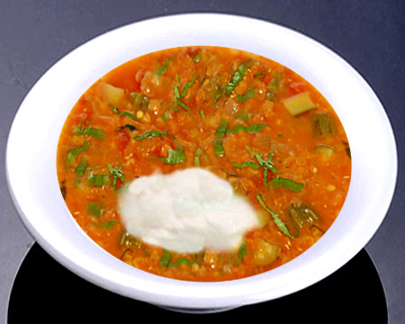 Суп из чечевицы с малосольными огурцами и черемшой в тарелке